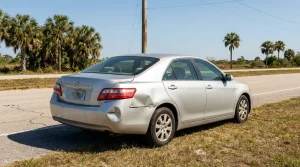 Toyota sedan with visible rear quarter panel collision damage parked roadside